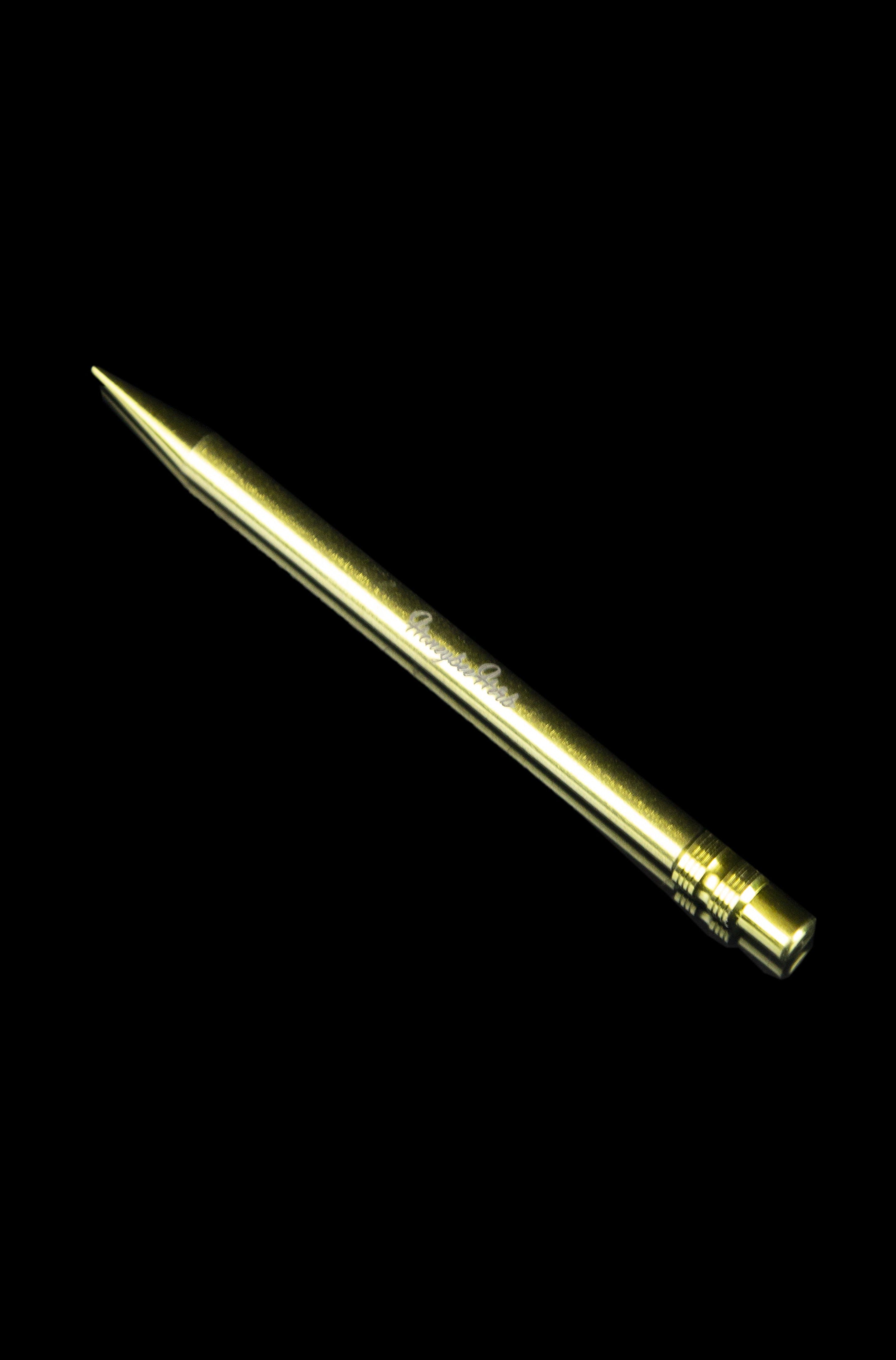 Gold cannabis dab tool on a black background.