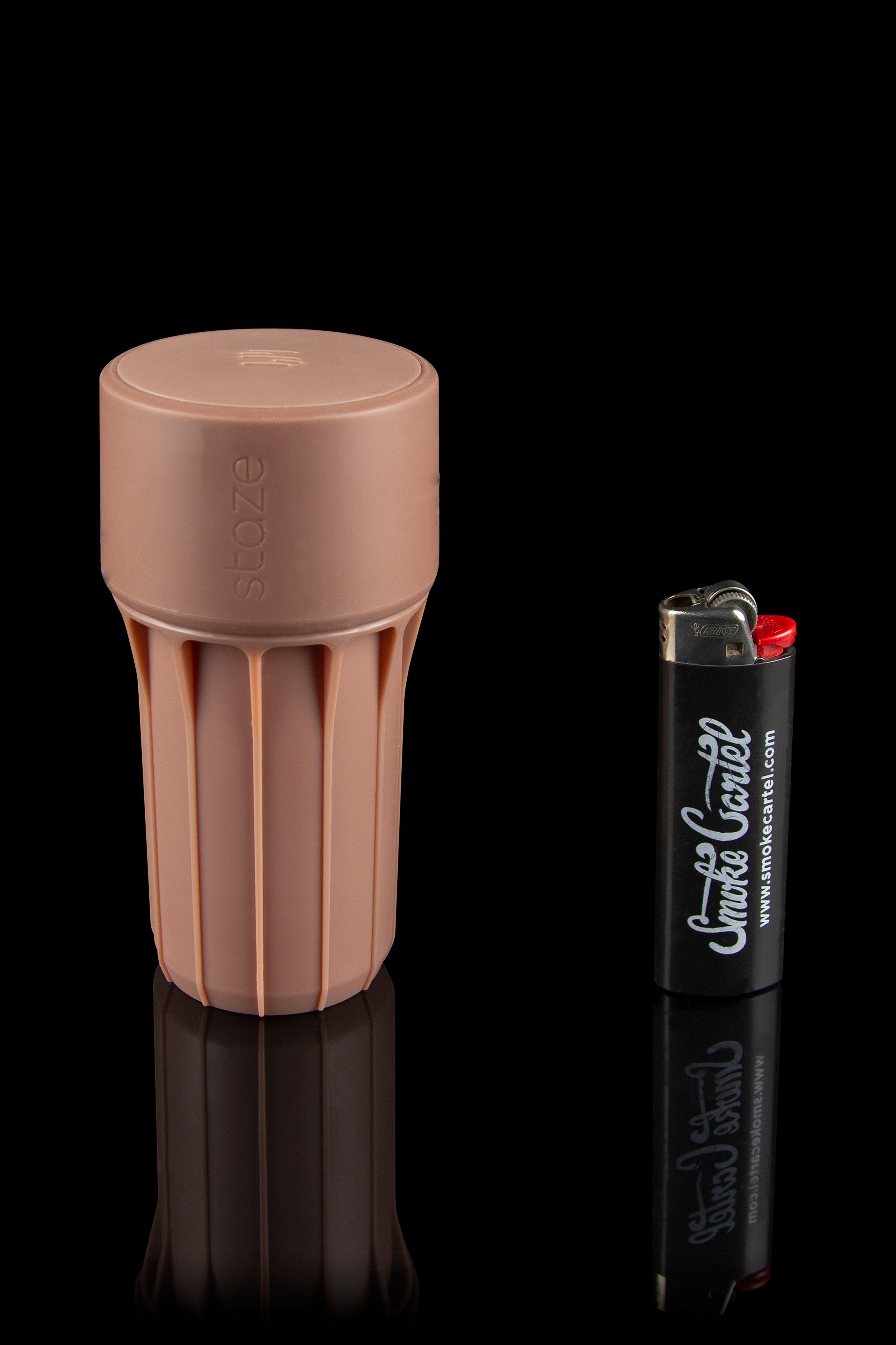 A terracotta-colored Storz & Bickel Mighty+ vaporizer alongside a branded lighter, reflected on a glossy black surface.