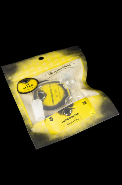 Clear plastic pouch containing a glass cannabis water pipe with floral designs, labeled "Honeycycle Herbs."