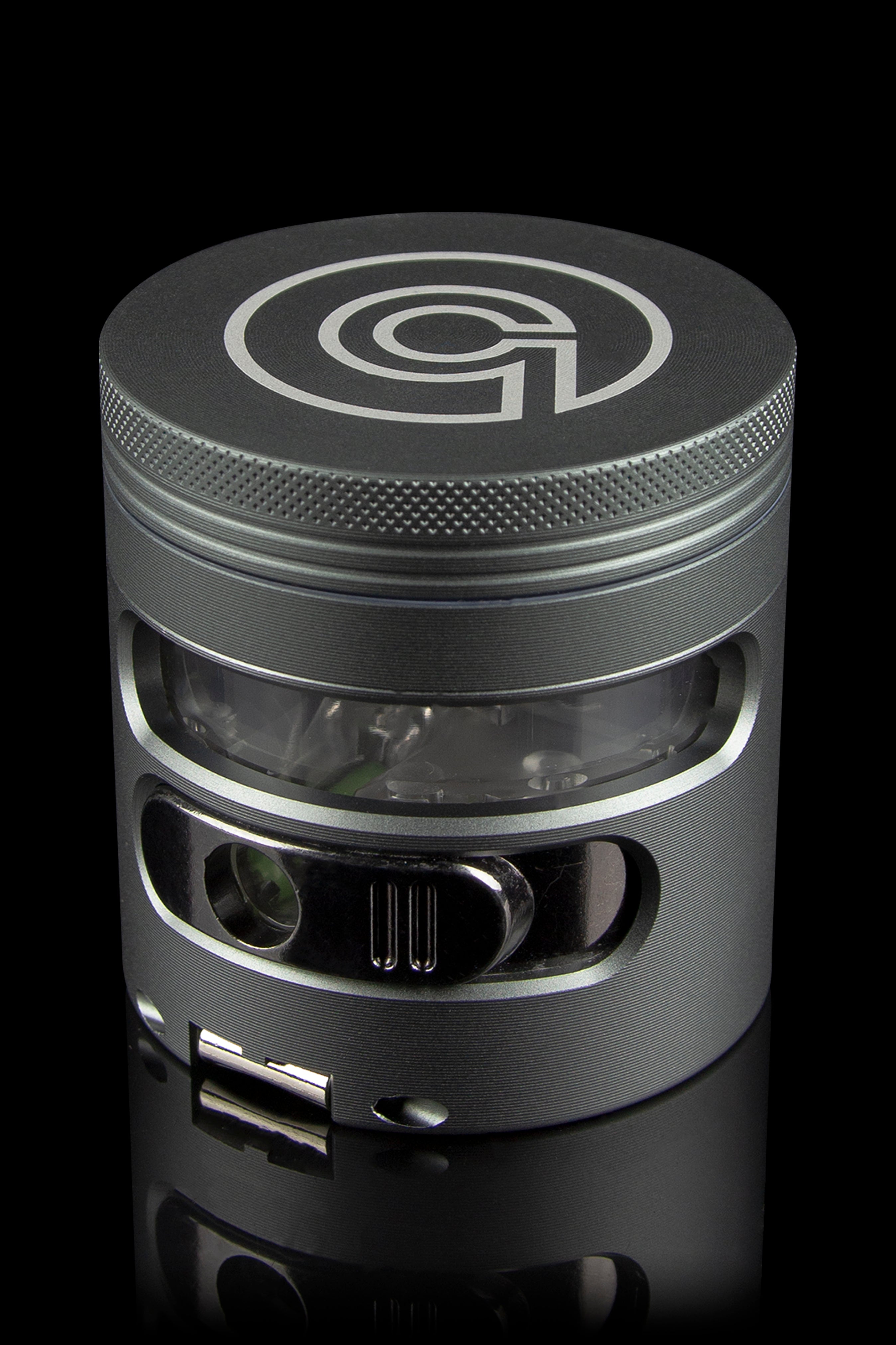 Black metal cannabis grinder with a clear central chamber, displaying ground plant material.