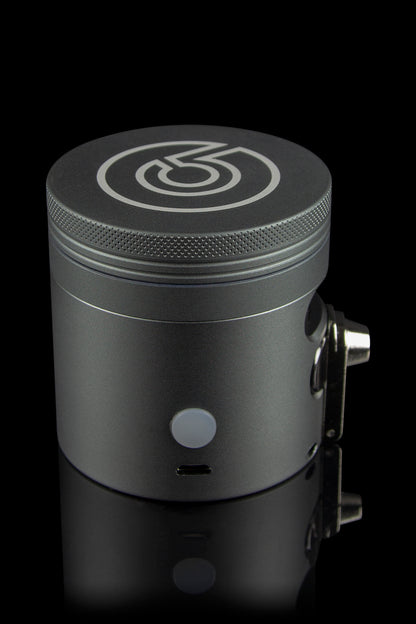 Sleek black cannabis grinder with a branded logo, displayed on a reflective surface.