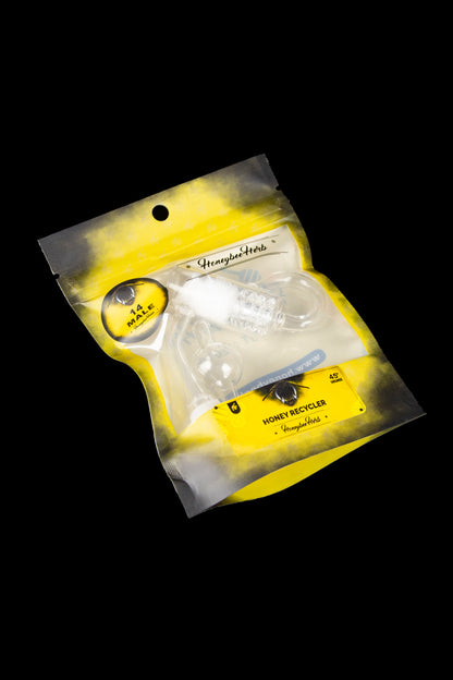 Sealed yellow mylar bag labeled “Honeybee Herbs” containing a glass cannabis oil recycler.