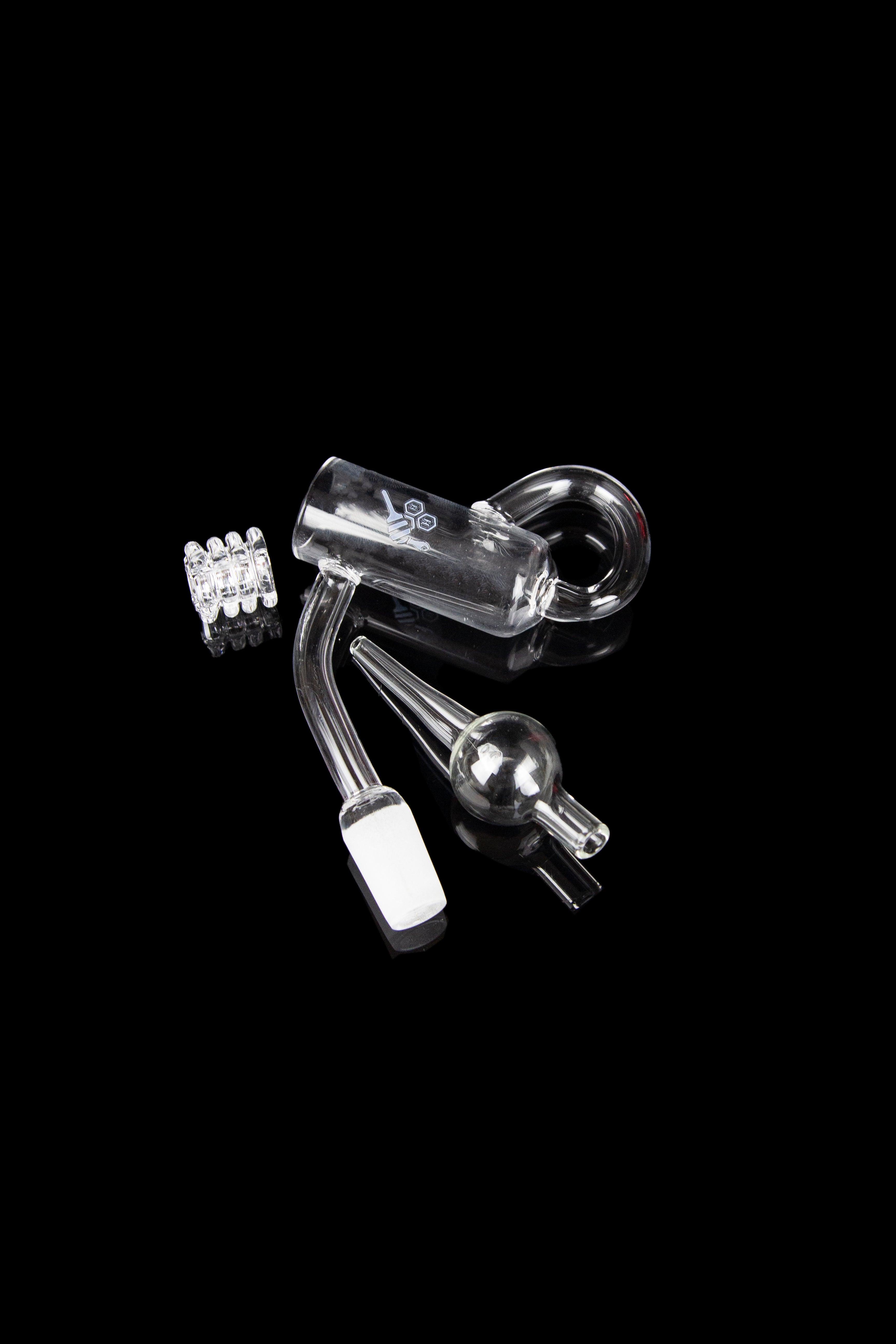 Clear glass dab rig components including a carb cap, banger, and downstem on a black background.