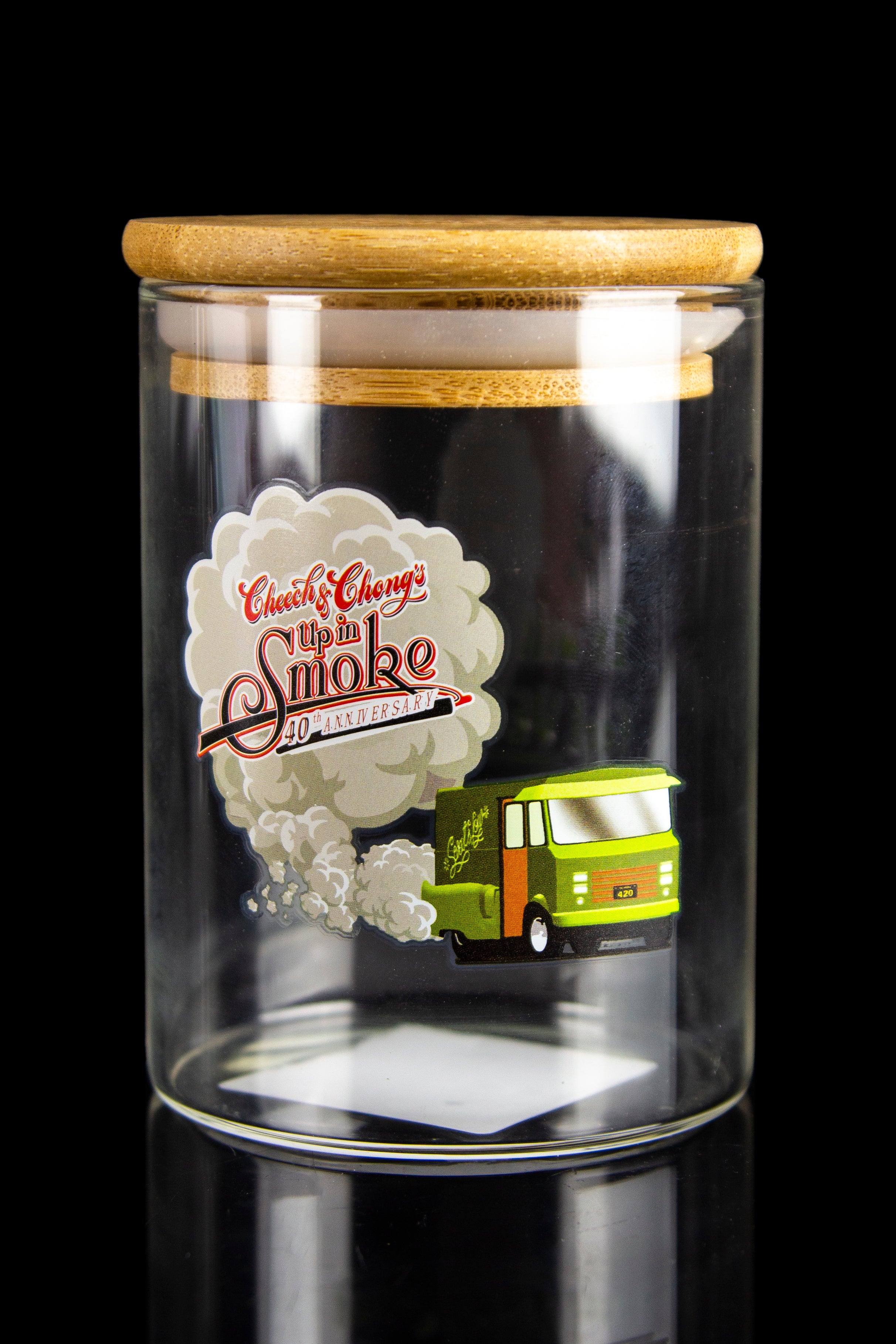 Glass jar display case featuring a miniature replica of the “Up in Smoke” tour bus with a commemorative 40th anniversary label, illuminated from below.