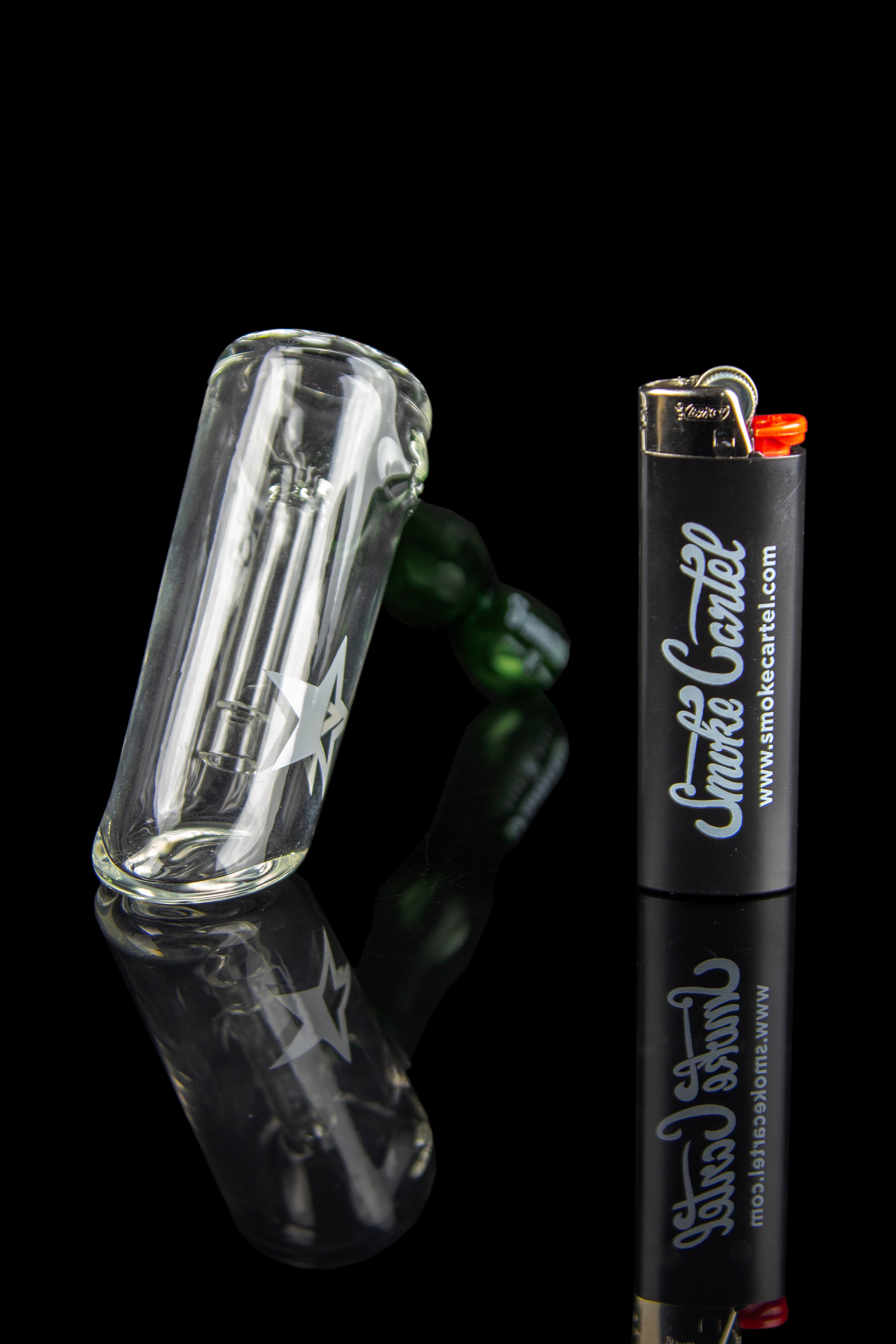 Angled close-up of the Famous X Straight Hammer Bubbler Pipe resting on a reflective black surface next to a black lighter.