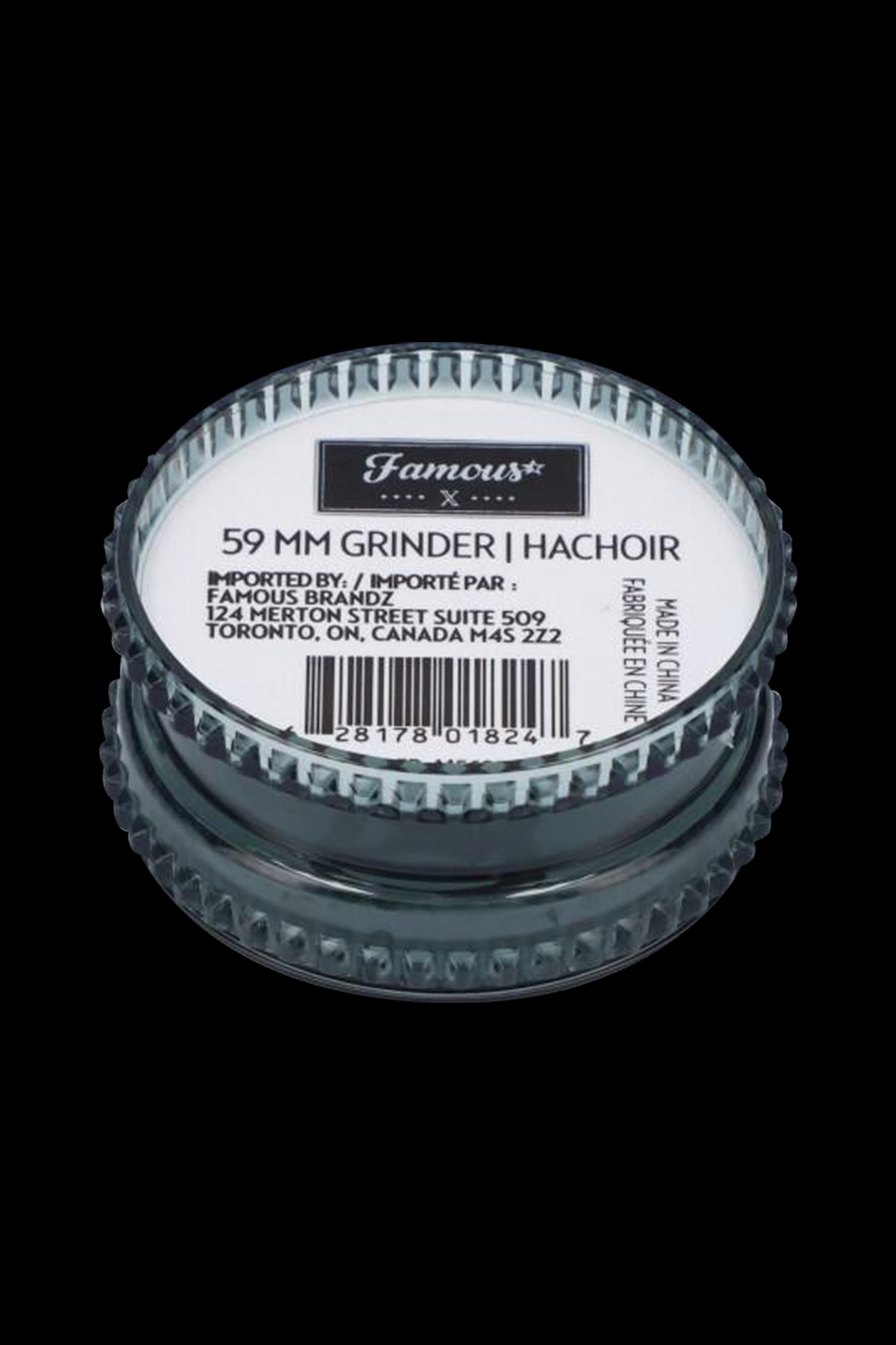 Close-up of a metallic cannabis grinder with label details including "59 MM GRINDER" and import information.