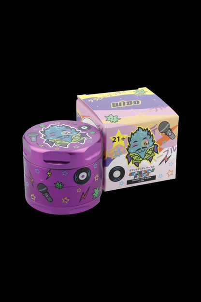 Pink cannabis grinder with a cartoon monster design, displayed with its packaging.