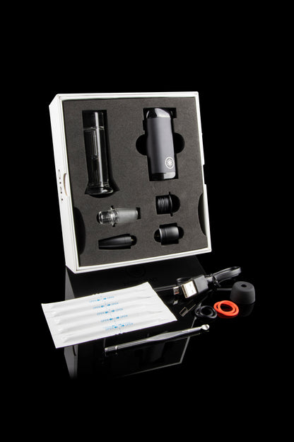 Cannabis vaporizer kit with device, attachments, cleaning tools, and replacement pads displayed in a foam insert.