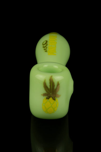 Glowing green cannabis oil vape pen with pineapple and leaf design.