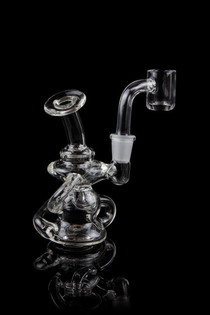 Clear glass dab rig with intricate sculptural design, reflecting on a black surface.