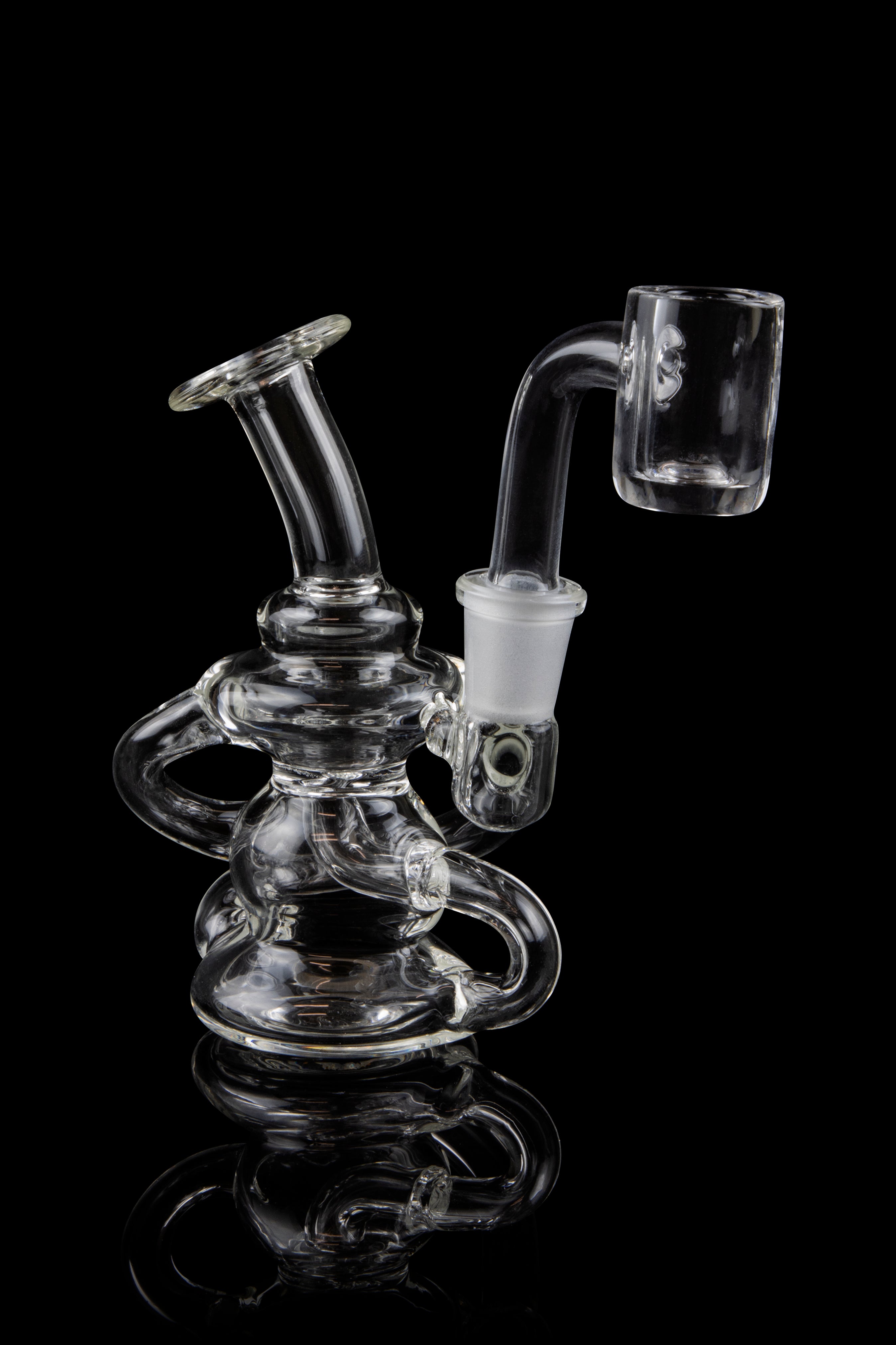 Clear glass dab rig with intricate looping design and quartz banger.