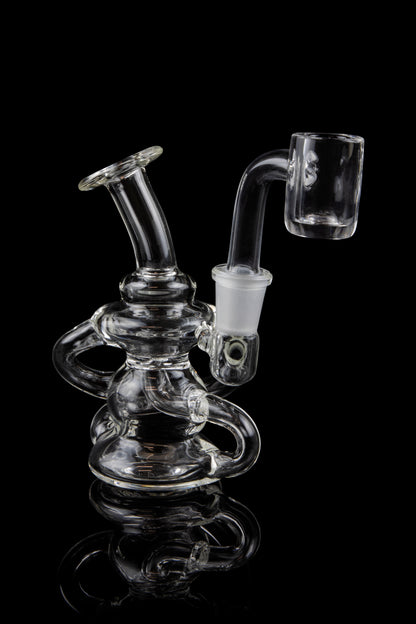 Clear glass dab rig with intricate looping design and quartz banger.