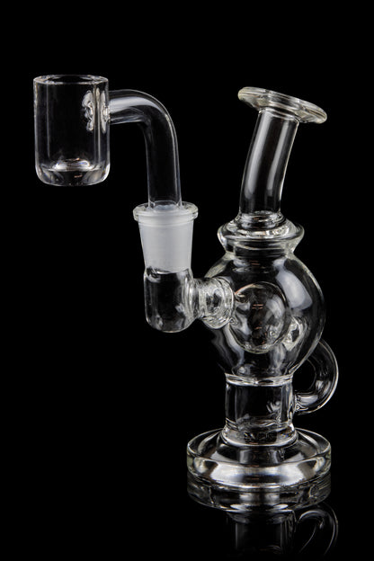 Clear glass dab rig with quartz banger, isolated on black.