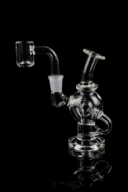 Clear glass dab rig with a quartz banger, isolated on a black background.