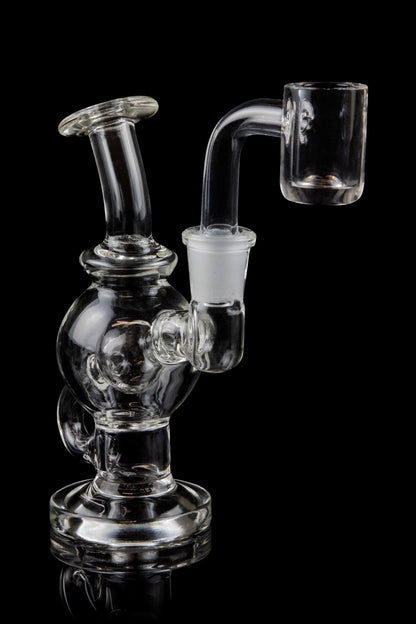 Clear glass dab rig with a quartz banger, isolated on a black background.