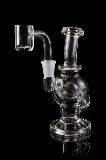 Clear glass dab rig with a quartz banger, isolated on a black background.
