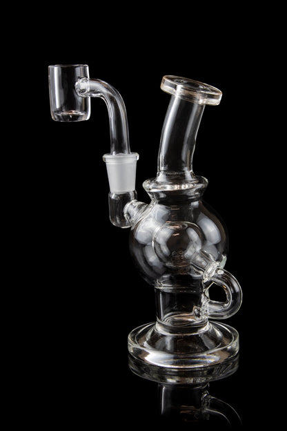 Clear glass dab rig with a bubbler and quartz nail, isolated on black.