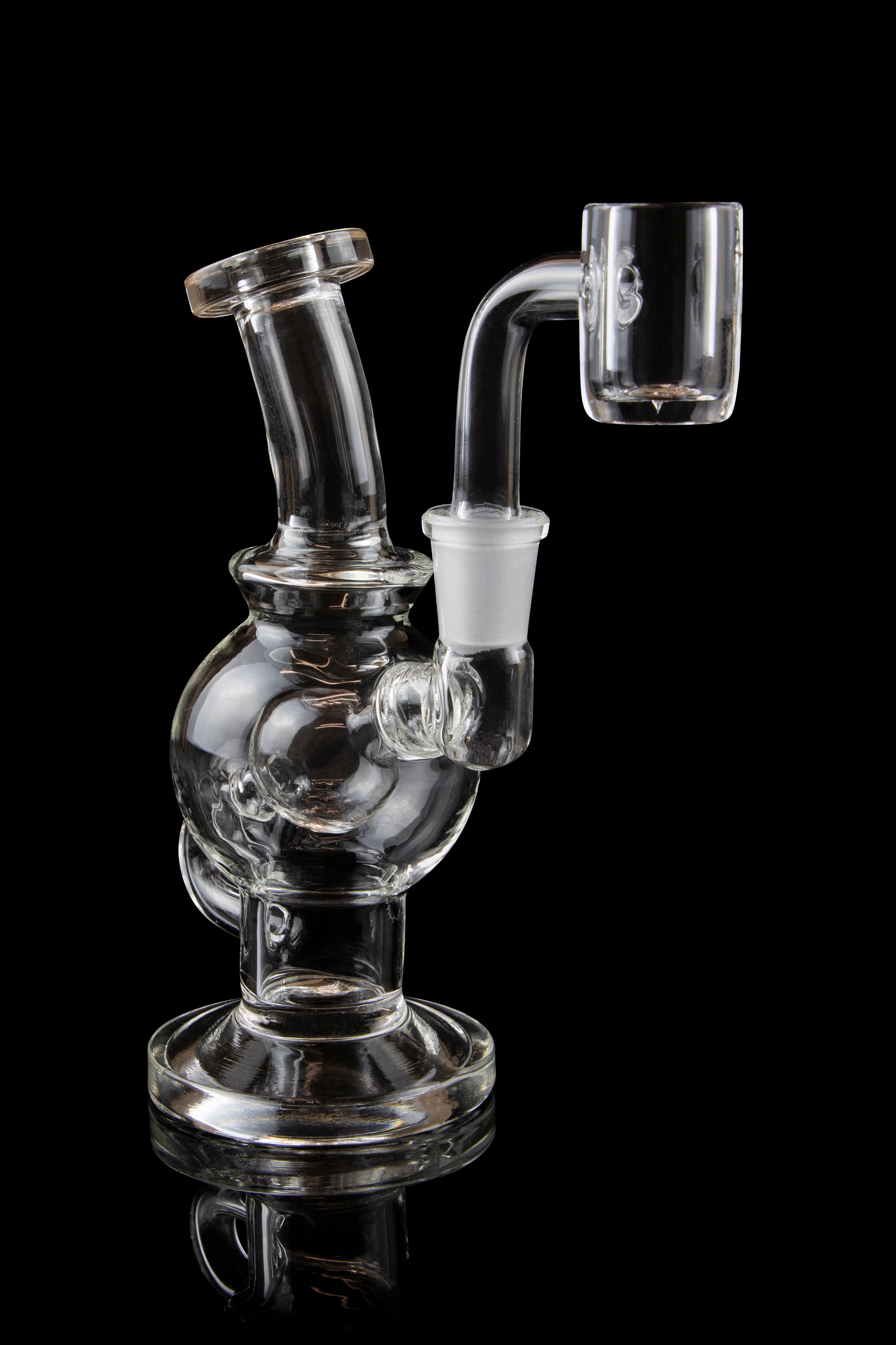 Clear glass dab rig with a quartz banger, isolated on a black background.