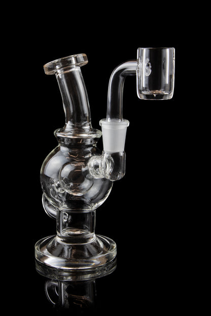 Clear glass dab rig with a quartz banger, isolated on a black background.
