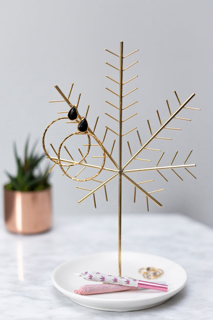 Gold cannabis leaf-shaped display stand with sunglasses and rolling papers on a marble tray.