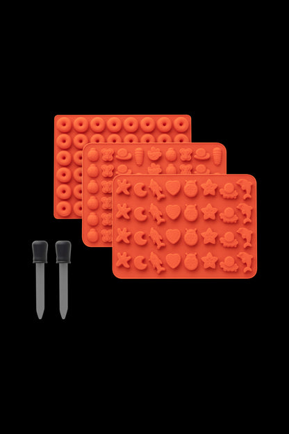 Red silicone molds with various cannabis-themed shapes and two dab tool applicators on a black background.