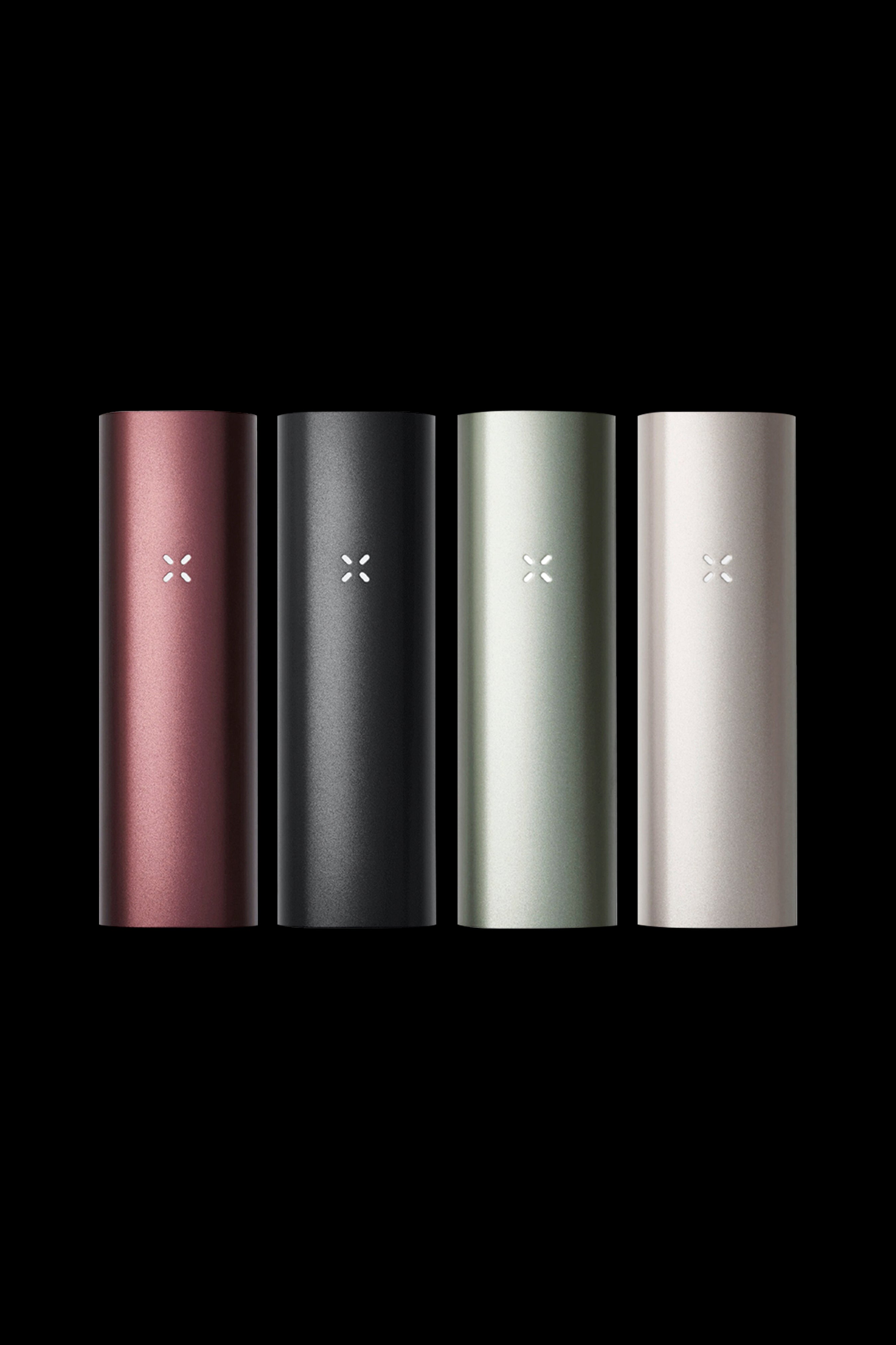 Four Pax Plus vaporizers in rose gold, black, sage green, and silver stand against a black background.
