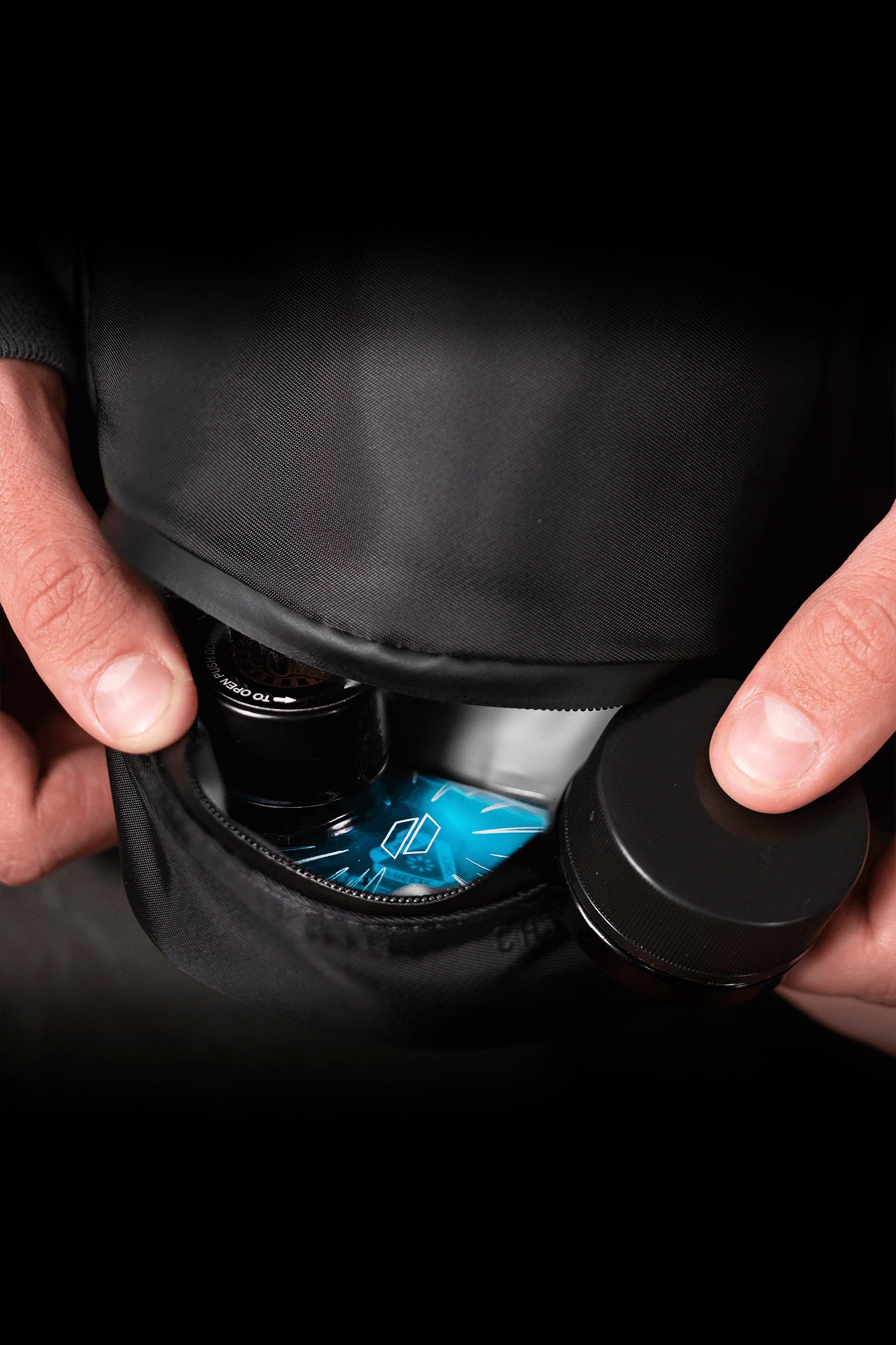 Hands holding a black cannabis vaporizer with a glowing blue digital display.