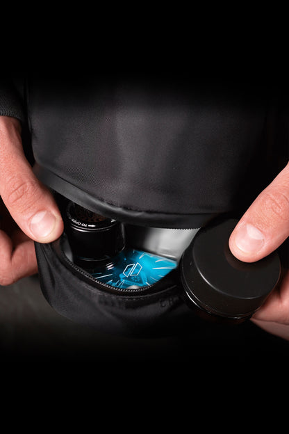 Hands holding a black cannabis vaporizer with a glowing blue digital display.
