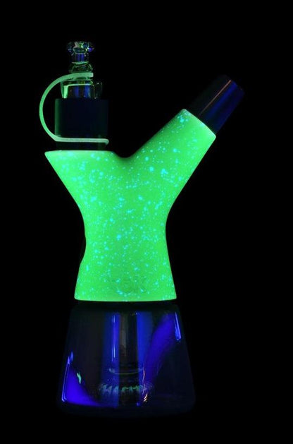 Glow-in-the-dark glass water pipe against a black background.