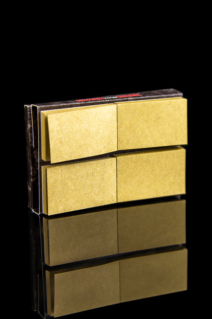 Gold rolling paper booklets stacked with a mirrored reflection on a black background.