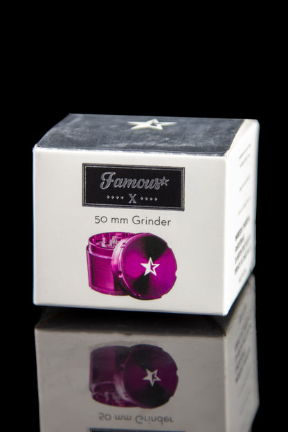 A close-up, angled view of the Famous X 4-Piece Grinder with a reflective surface and minimalist design.