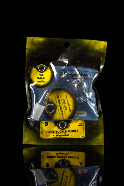 Silver mylar bag of "Honeysuckle Herbs" cannabis concentrate with branding and product details, against a black background.