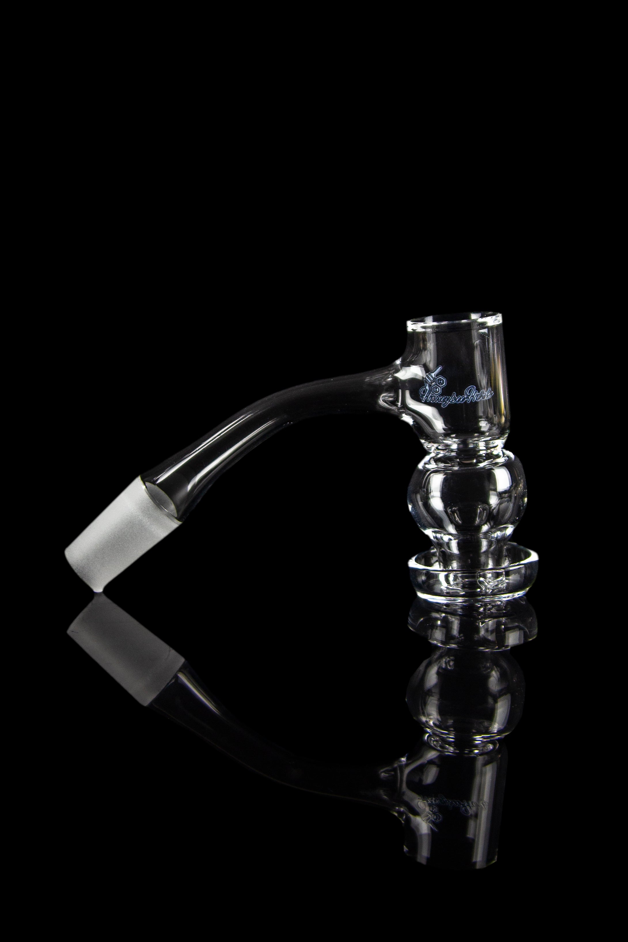 Clear glass bubbler with angled mouthpiece and textured body, reflecting on a black surface.