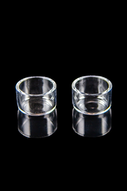 Two clear glass inserts for use with cannabis dab rigs, displayed on a black reflective surface.