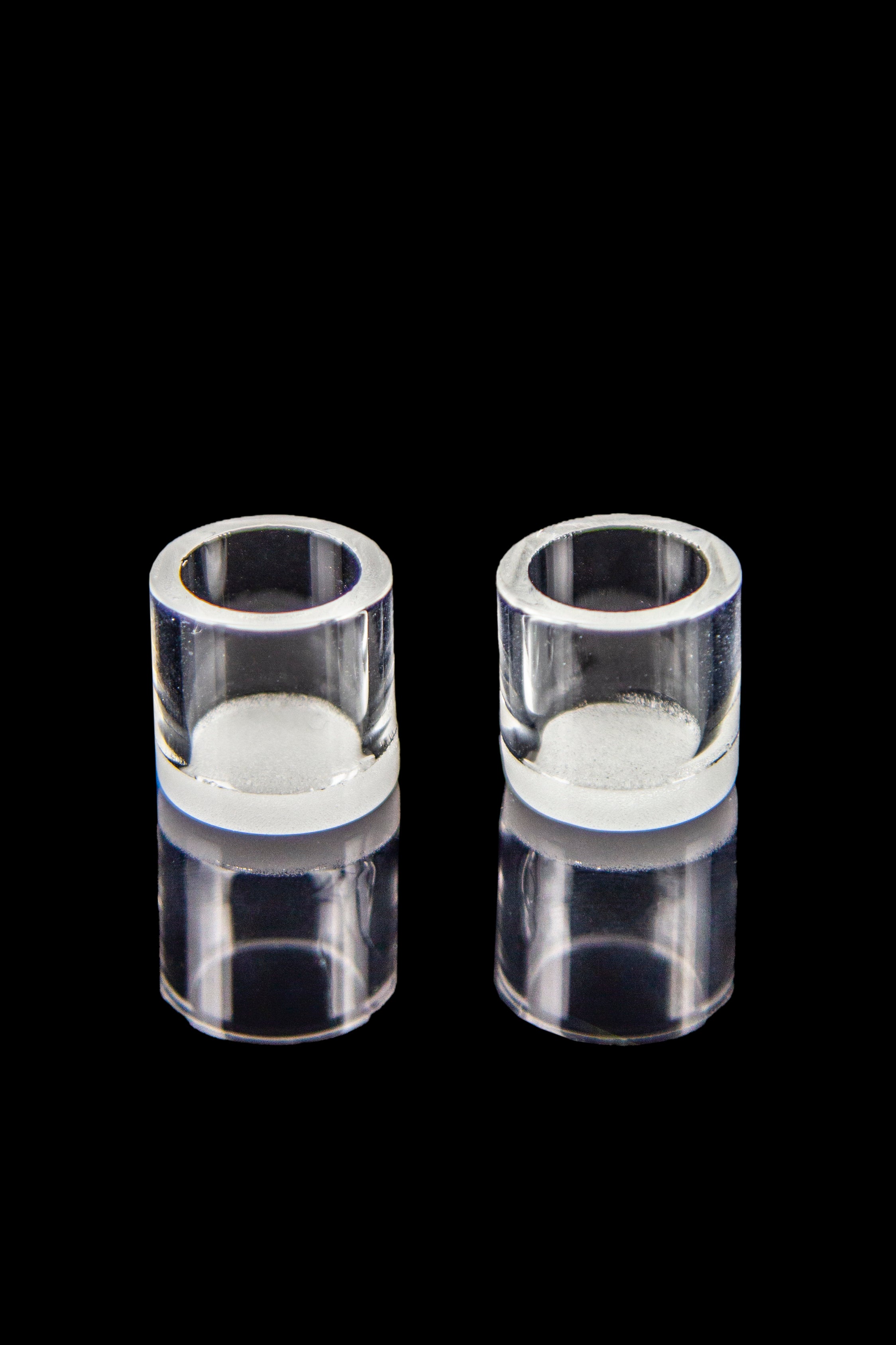 Clear quartz bongs with residual cannabis concentrate visible inside, isolated on black.