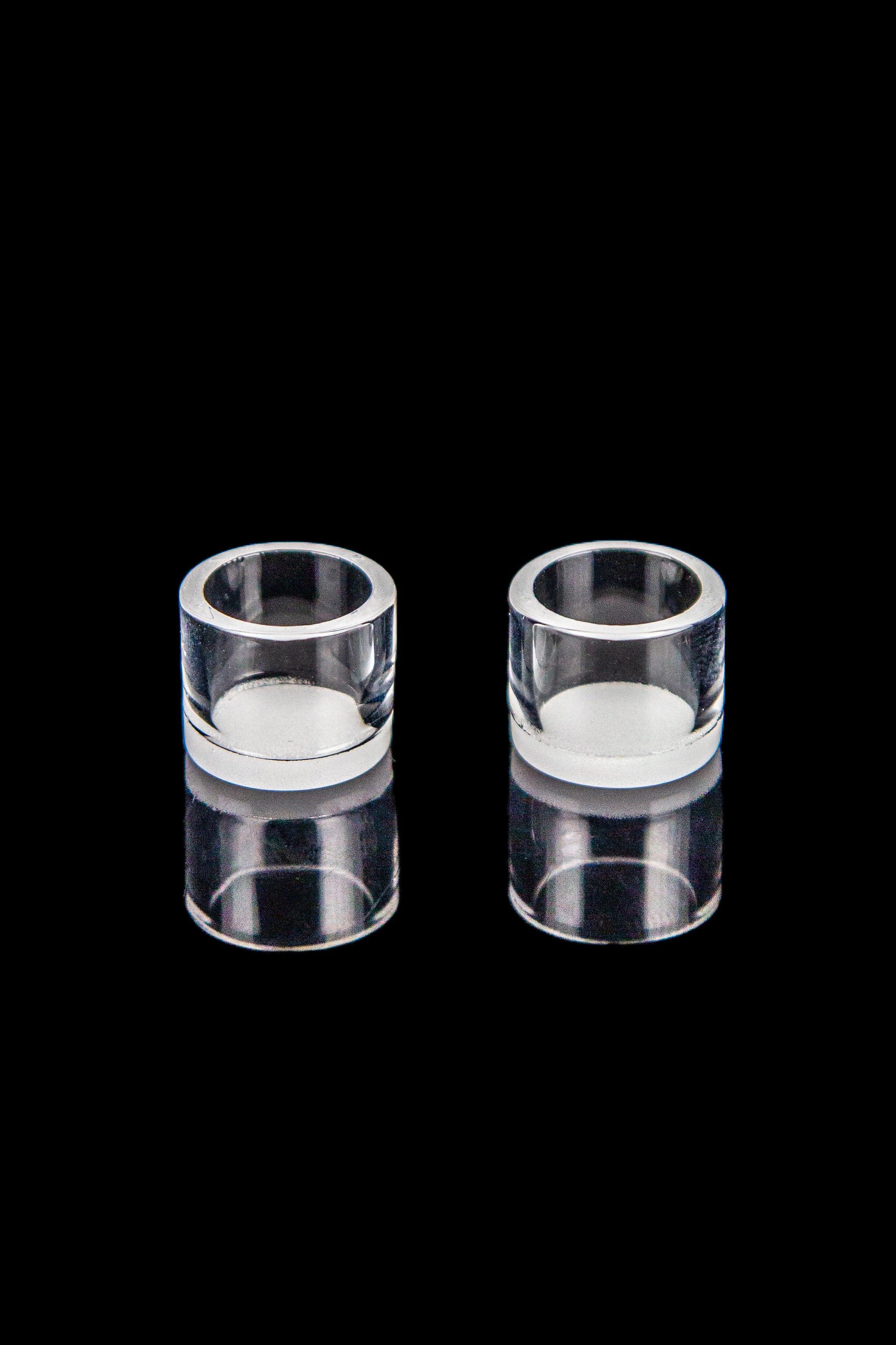 Two clear quartz bongs against a black background.