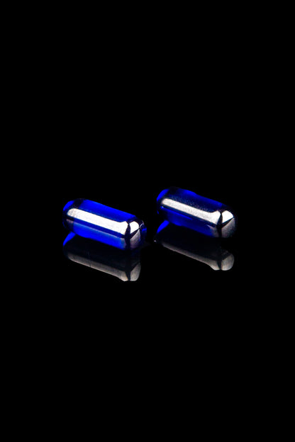 Blue glass oil rig tips reflecting on a black surface.