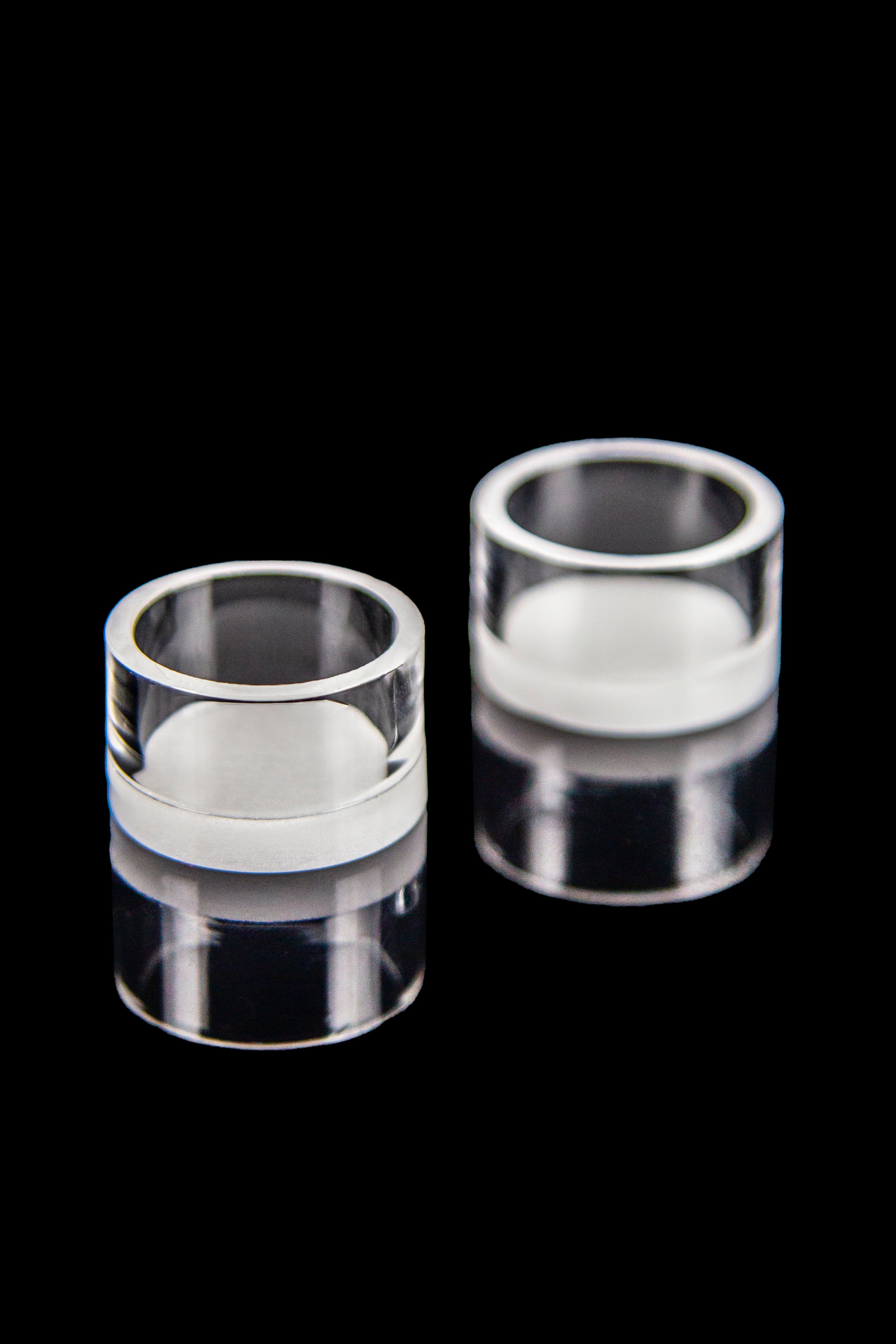 Clear quartz bongs with white interior components, isolated on a black background.