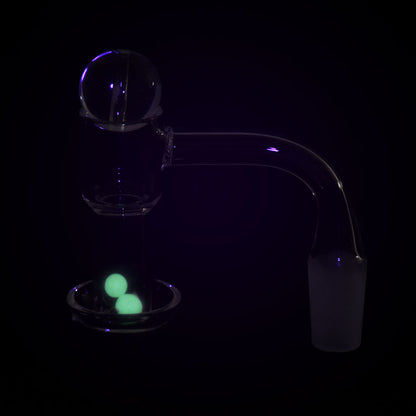 Side view of the Quartz Banger with Ball Carb Cap & Glow Terp Beads Set showing a glass quartz banger and ball carb cap with two glowing green terp beads in the dish.