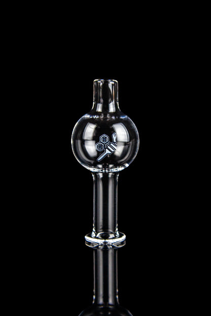 Clear glass dab rig cap with etched logo, isolated on black.
