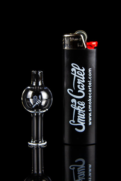 Black glass dab rig with spherical cap next to a black lighter branded with “Smokecartel.com” against a black background.