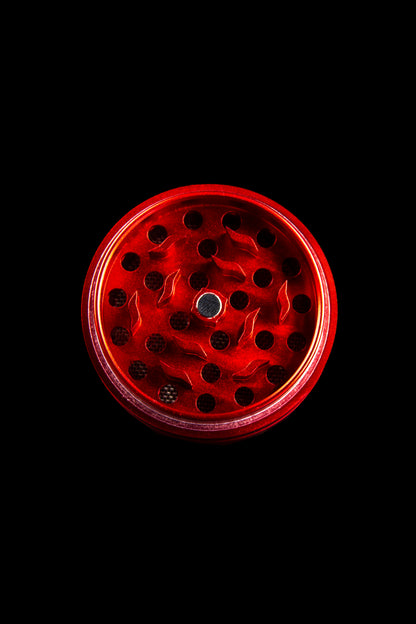 Red cannabis grinder isolated on a black background.