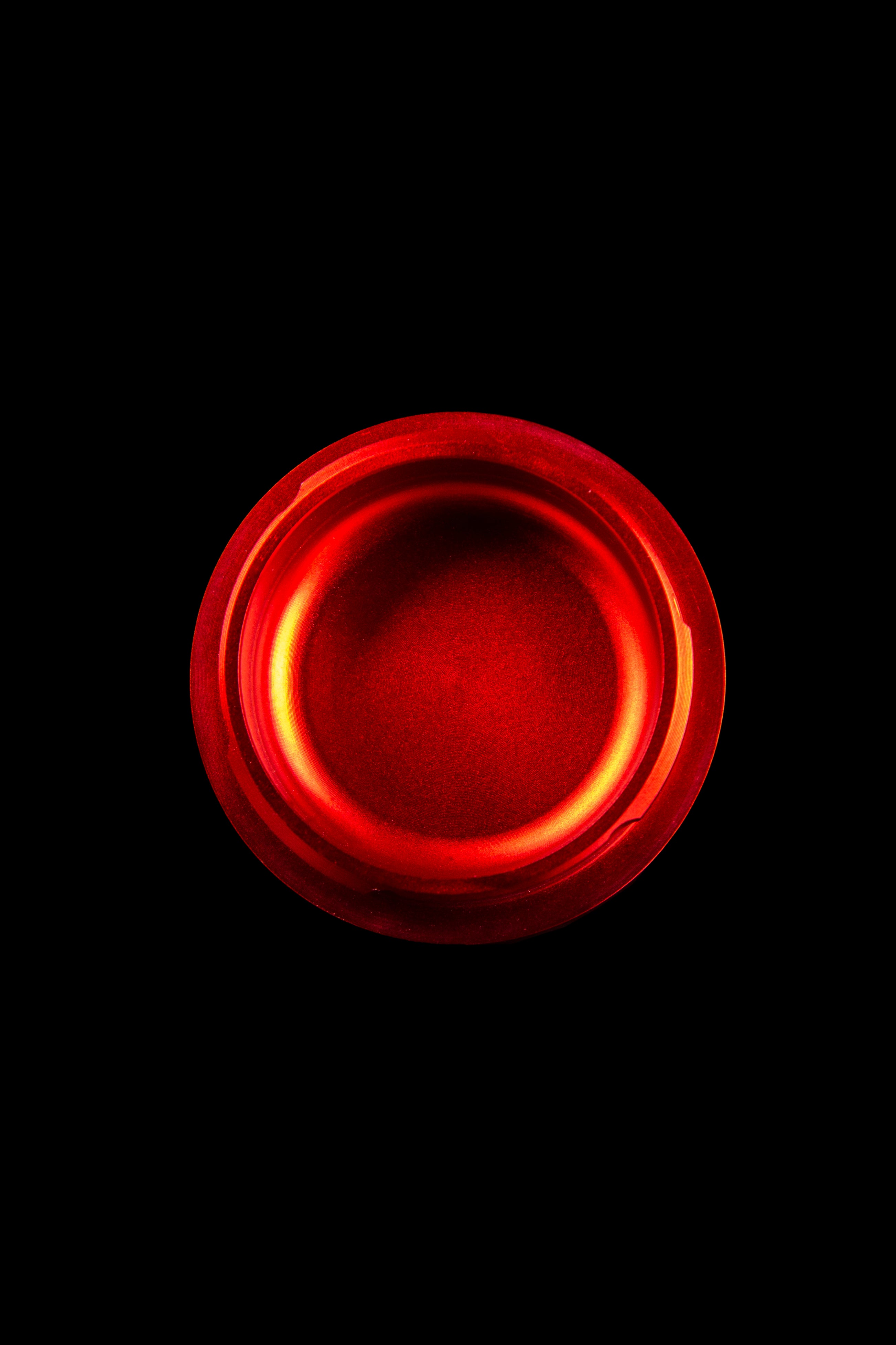 Red glass ashtray isolated on black.