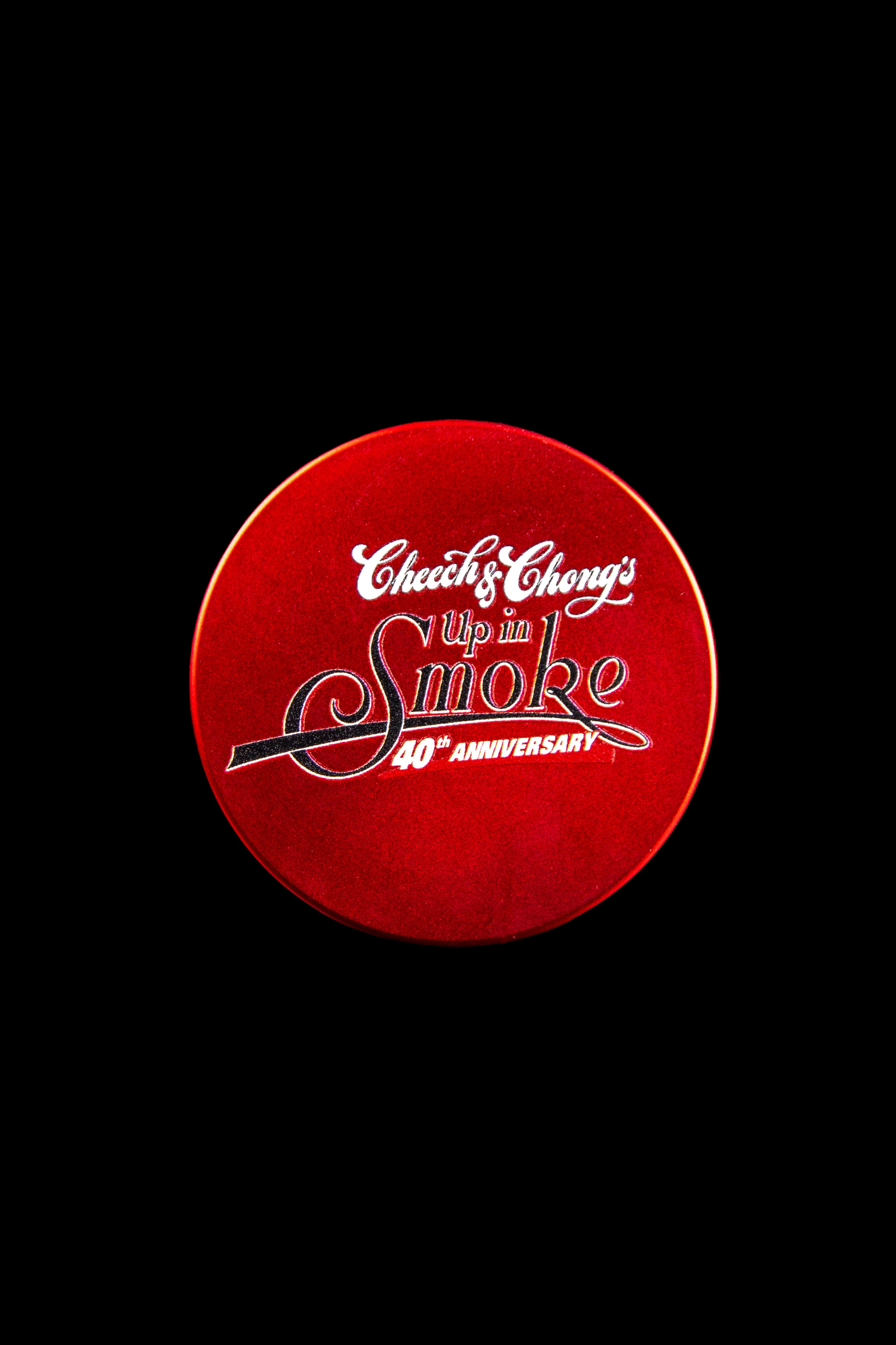 Red metal grinder with “Cheech & Chong’s Up in Smoke 40th Anniversary” logo.
