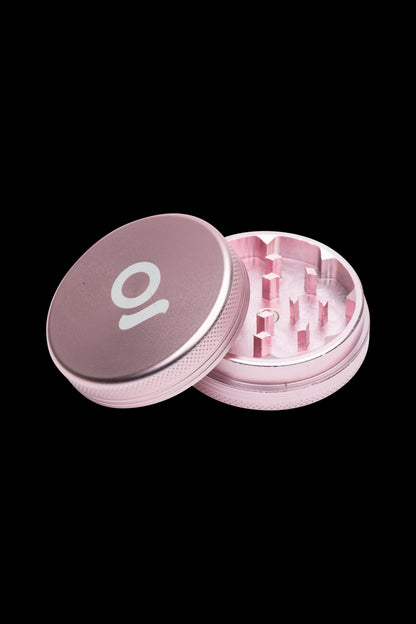 Rose gold cannabis grinder with open lid revealing teeth and chamber.