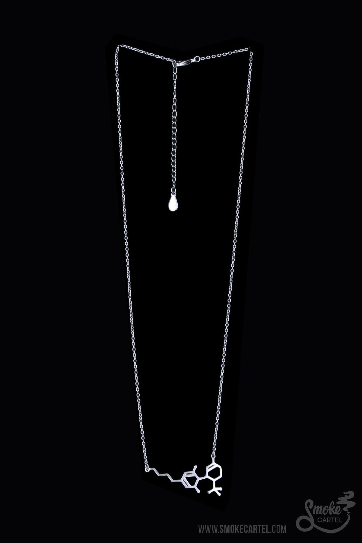 The Smoke Cartel THC Molecule Necklace hangs delicately against a plain black backdrop, showcasing its minimalist design.