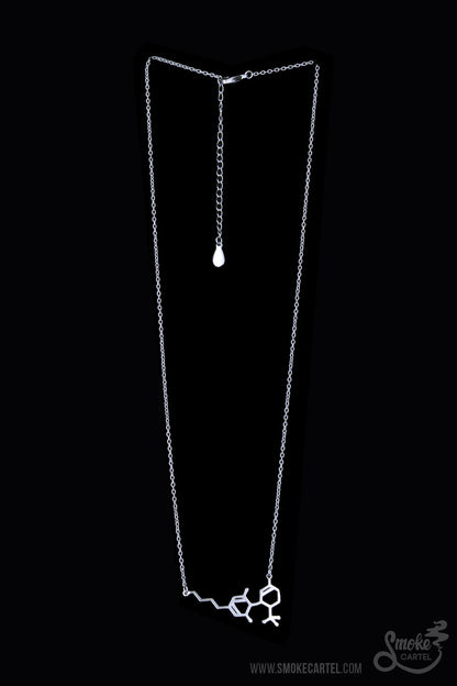 The Smoke Cartel THC Molecule Necklace hangs delicately against a plain black backdrop, showcasing its minimalist design.