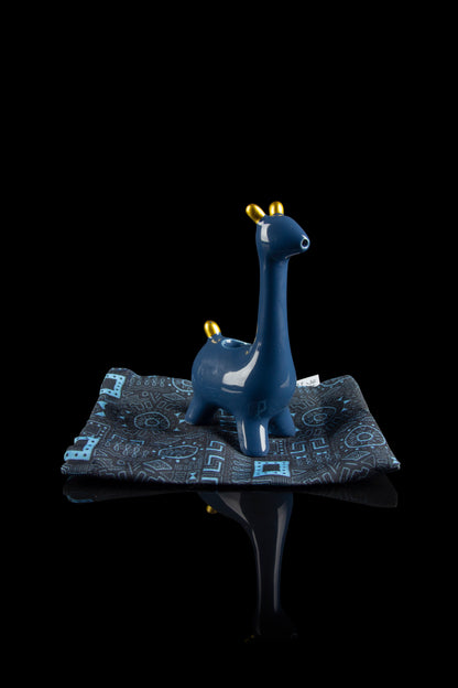 Blue giraffe-shaped water pipe resting on a patterned cloth with a reflective surface.