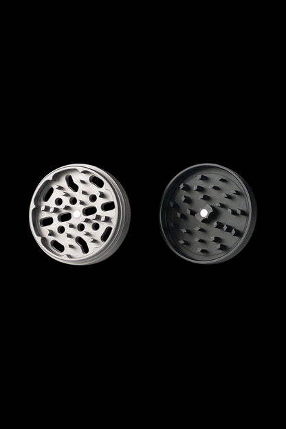 A top-down view of the Kannastor 4-Piece Solid Body Grinder, showcasing its metallic, multi-tiered design against a dark backdrop.