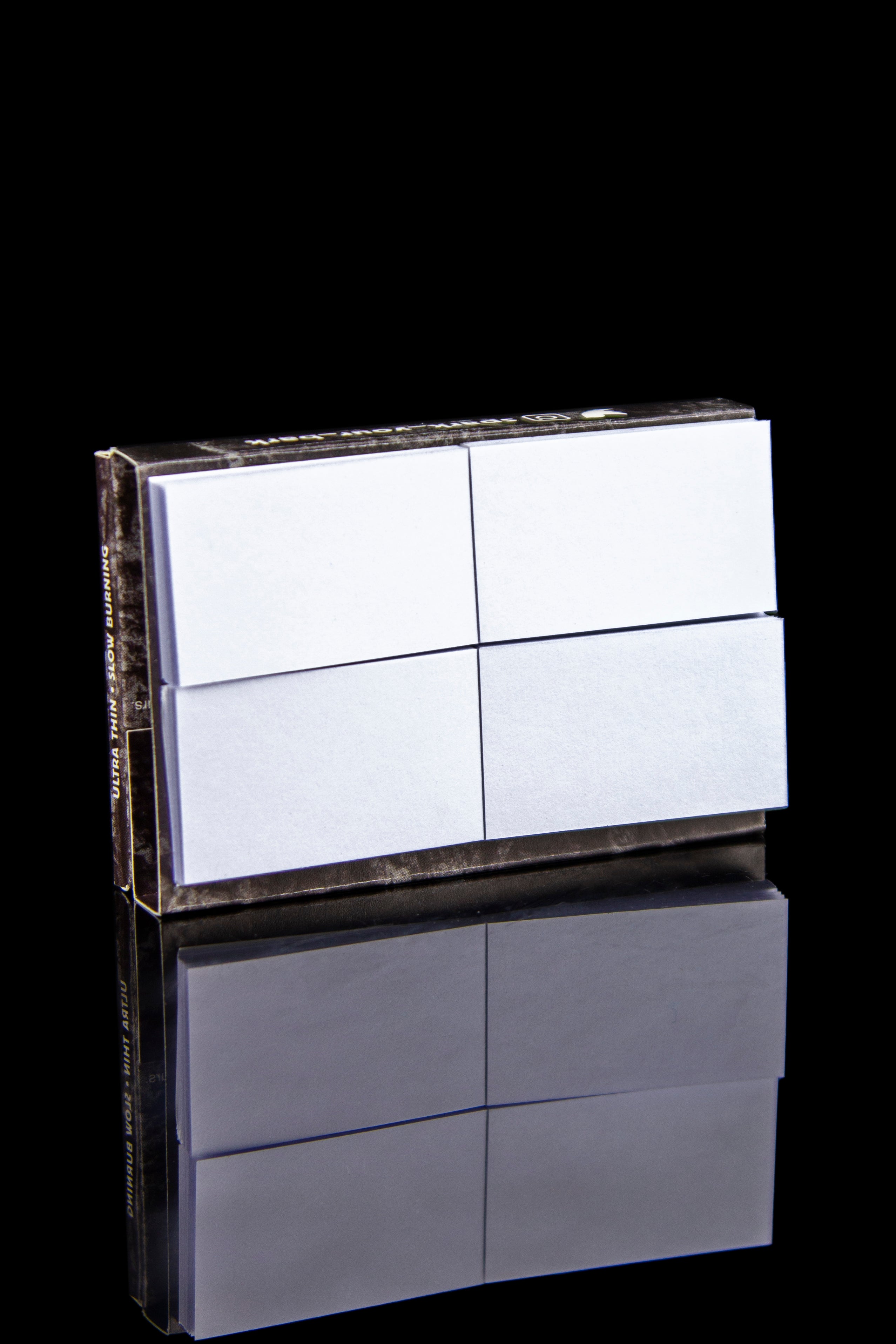 Stack of pre-rolled hemp filter tips with a mirrored reflection on a black surface.